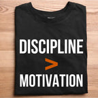 Black t-shirt with 'DISCIPLINE > MOTIVATION' text on a wooden surface
