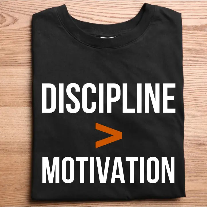 Black t-shirt with 'DISCIPLINE > MOTIVATION' text on a wooden surface